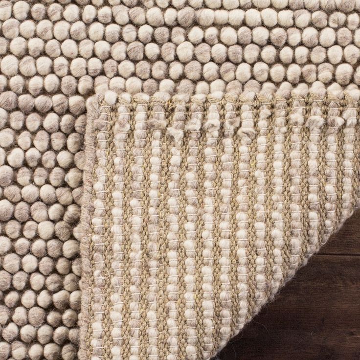 an area rug with white balls on the top and beige dots on the bottom, along with a wooden floor