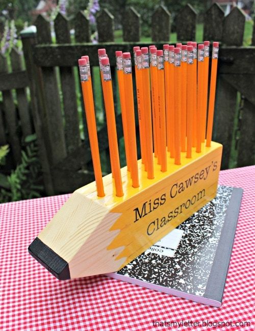 an orange pencil holder on top of a red and white checkered table cloth with wooden sticks sticking out of it