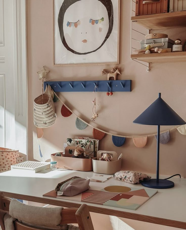 a desk with a lamp and pictures on the wall above it, along with other items