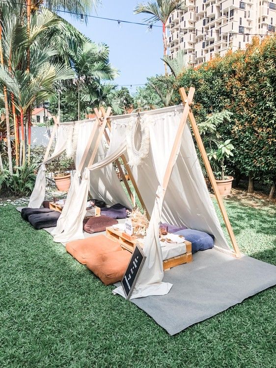 a tent set up in the middle of a lawn with pillows and blankets on it