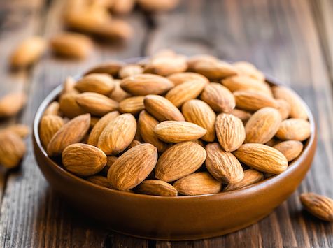 a wooden bowl filled with almonds on top of a table