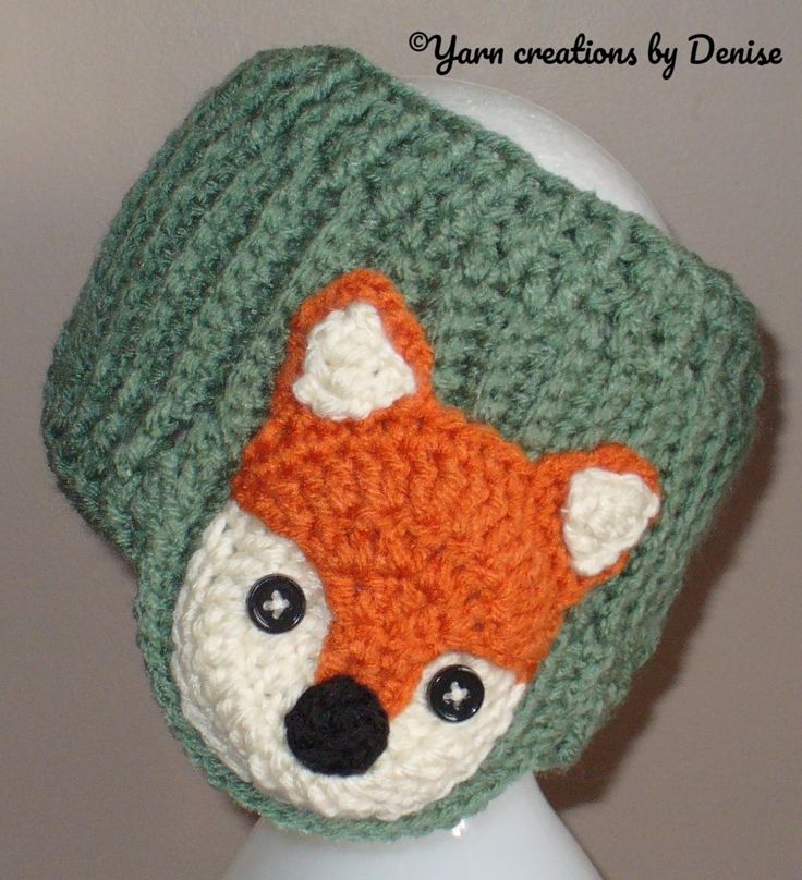 a crocheted hat with an orange and white fox on it's face