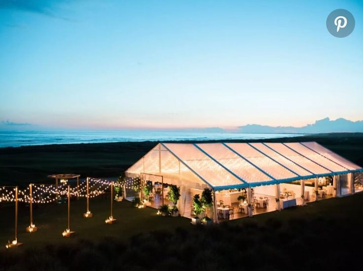 an aerial view of a tent set up for a wedding at dusk with string lights