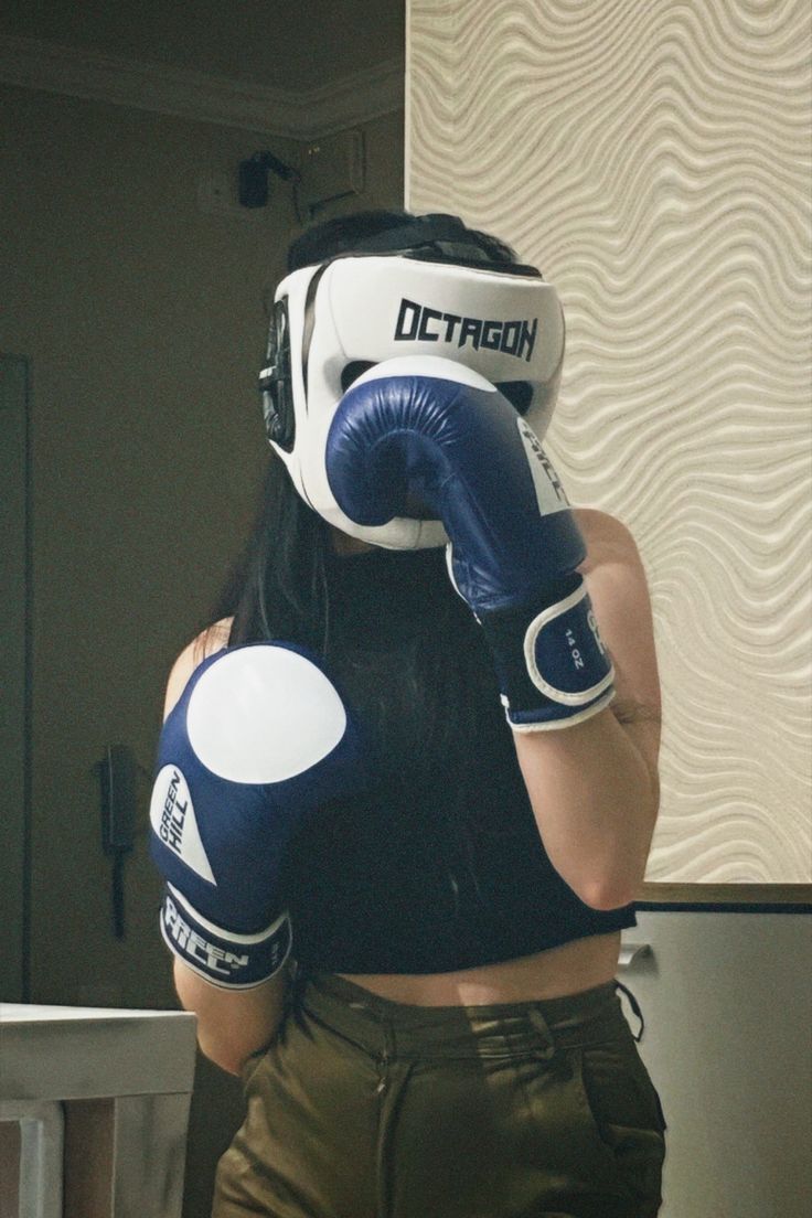 a woman with long hair wearing boxing gloves and holding a punching glove up to her face