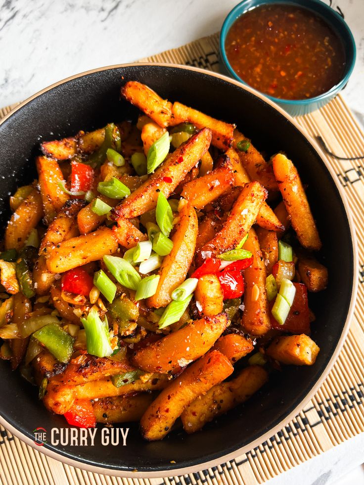 a bowl filled with fried vegetables next to a small bowl of dipping sauce on the side