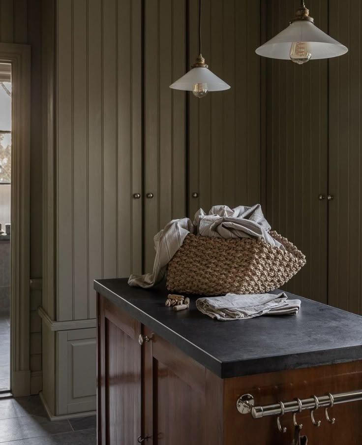 a kitchen island topped with a basket and two hanging lights