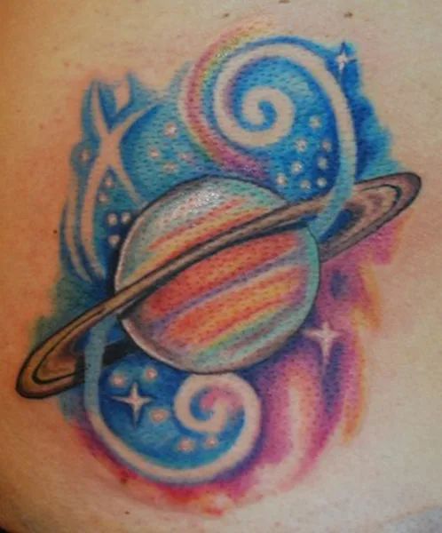 saturn tattoo on the side of a woman's stomach with stars and swirls around it