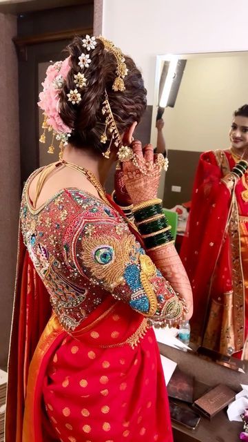 a woman standing in front of a mirror with her hands on her face and wearing a red sari