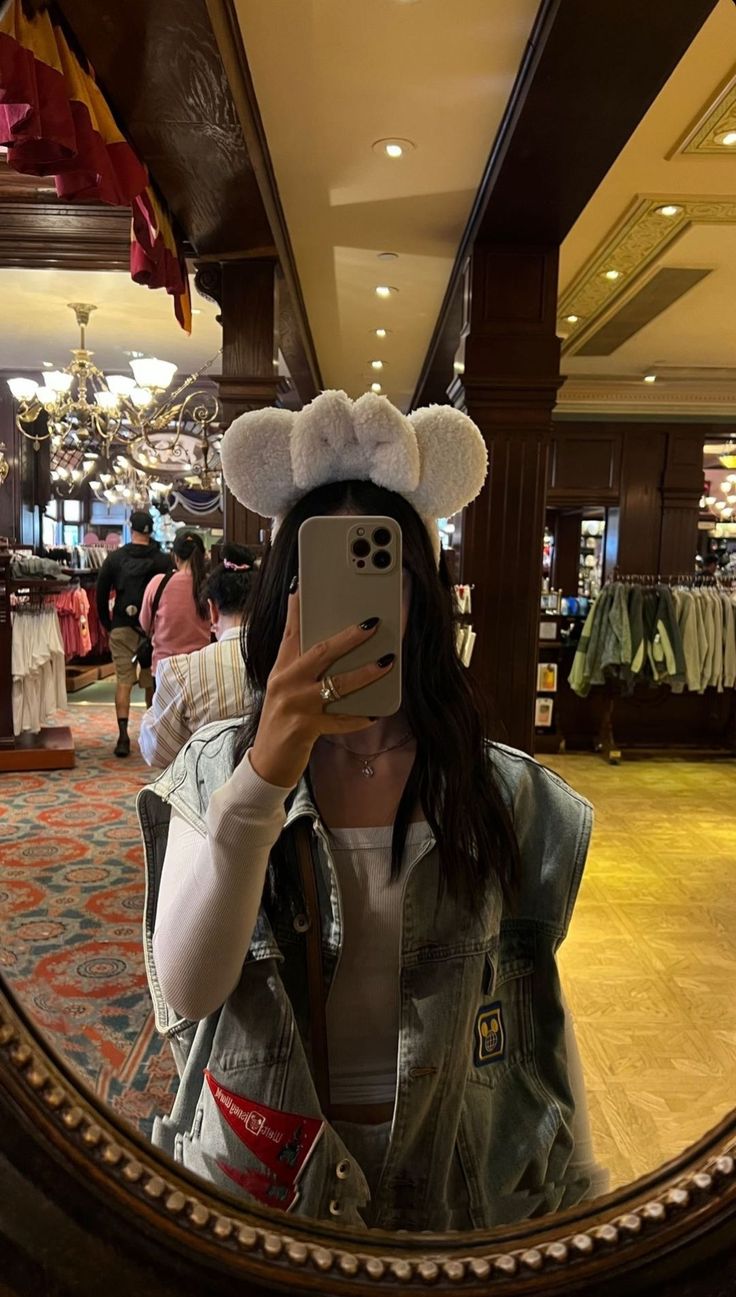 a woman taking a selfie with her cell phone in front of a mirror at a store