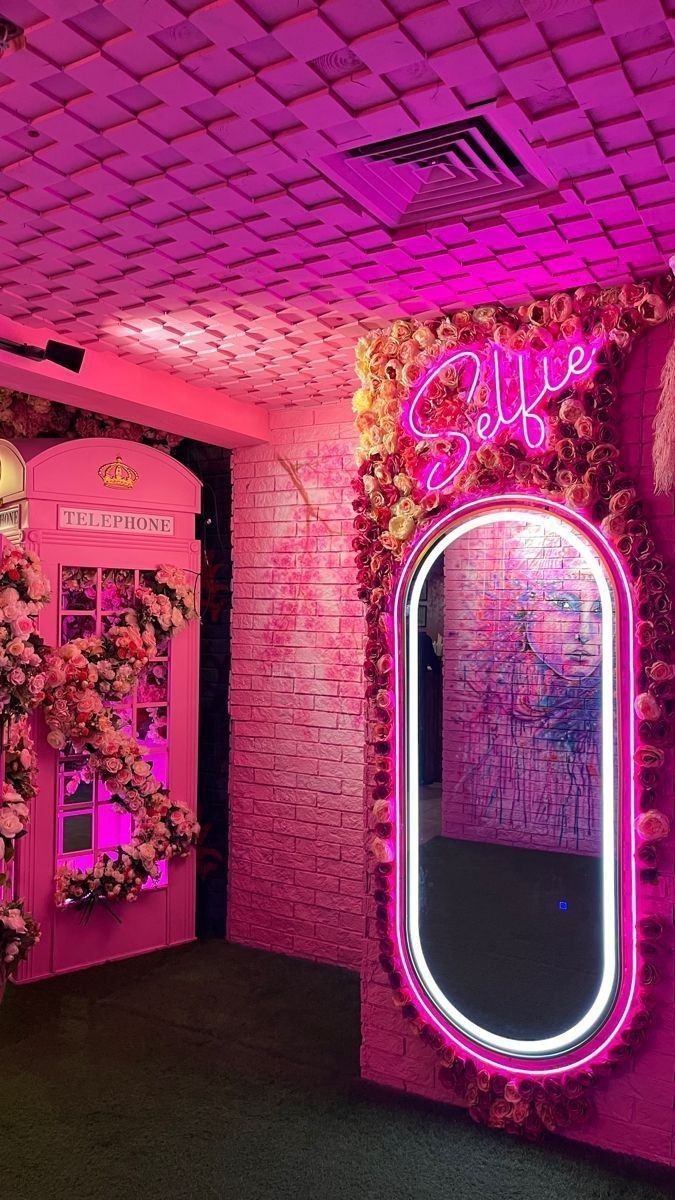 the pink room is decorated with flowers and greenery, along with a large round mirror