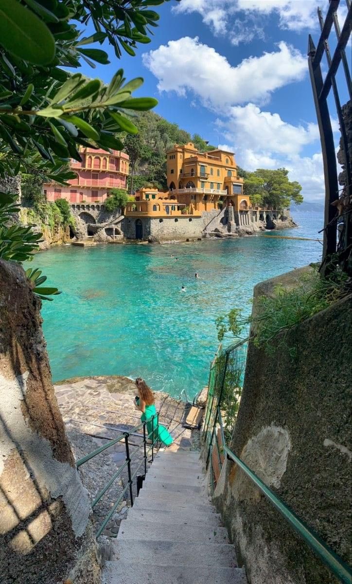 stairs lead down to the beach with houses in the background and clear blue water on either side