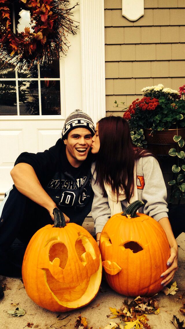 a man and woman sitting next to each other with carved pumpkins