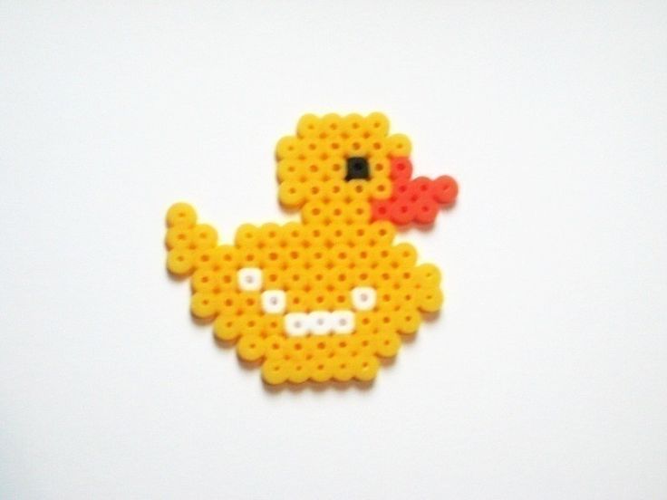 a yellow bird made out of legos sitting on top of a white table next to a red object