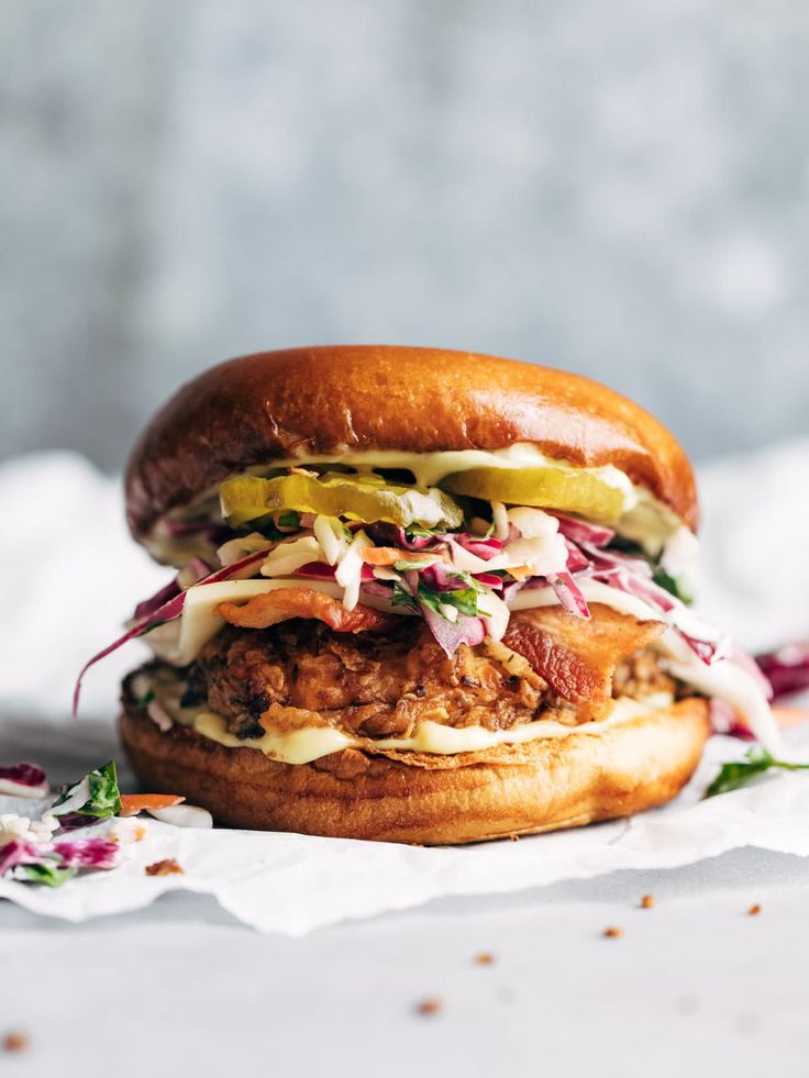 a chicken sandwich with coleslaw and pickles on it sitting on a napkin