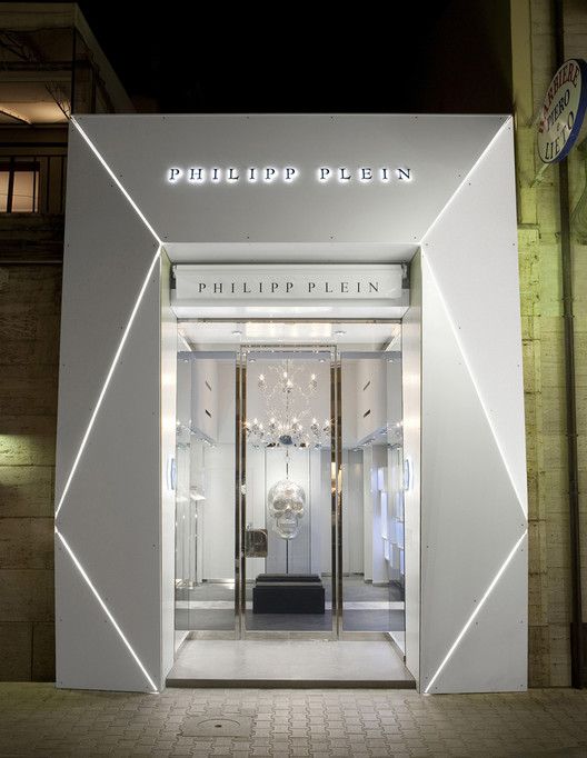 the front entrance to a luxury store with lights shining on it's glass doors