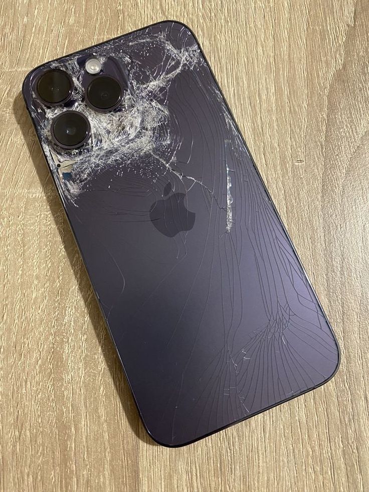 an iphone that has been broken and is sitting on a table with the screen cracked off