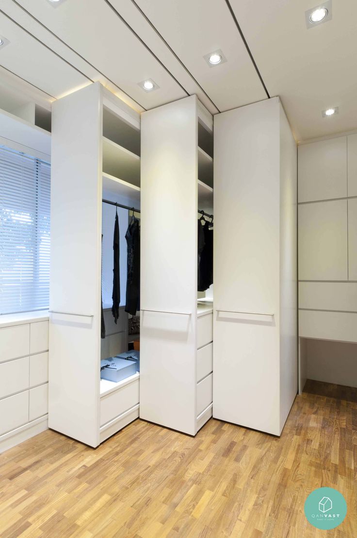 an image of a white closet with clothes hanging on the doors and drawers in it