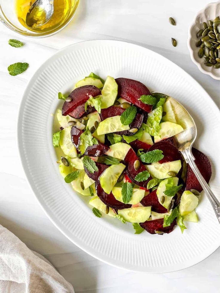 a white plate topped with sliced beets and cucumbers