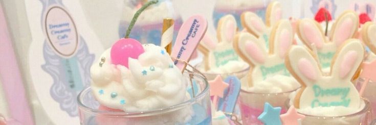 some bunny ears are on top of marshmallows in small cups with candy sticks sticking out of them