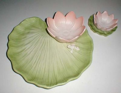 two pink and green lotus shaped dishes sitting on top of a white countertop next to each other