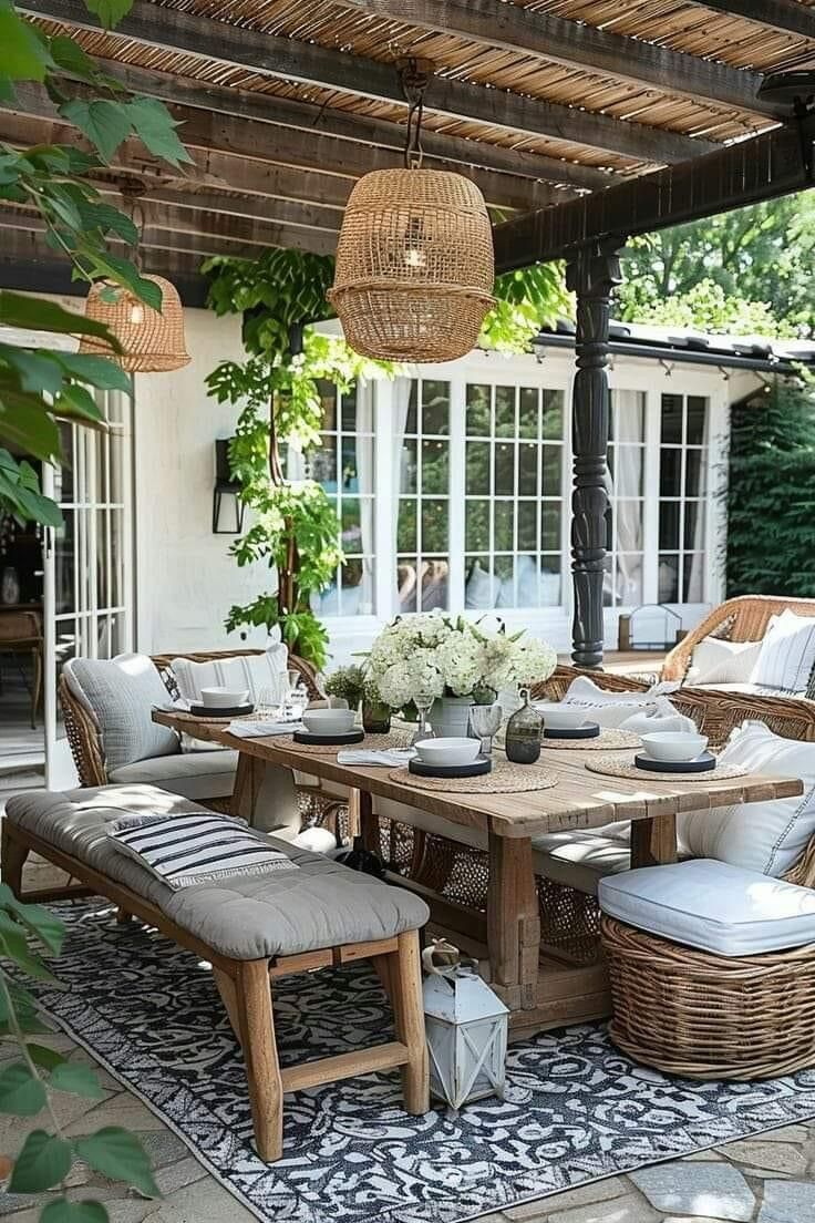 an outdoor dining area with wicker furniture and white flowers in vases on the table