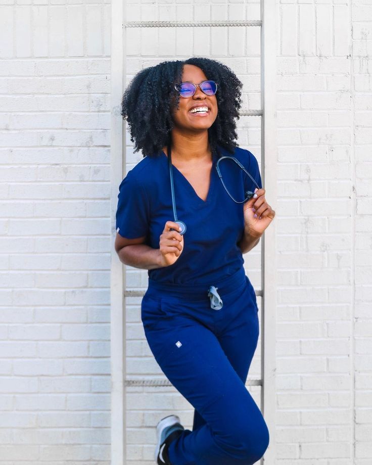 a woman in blue jumpsuits holding a tennis racket and smiling at the camera