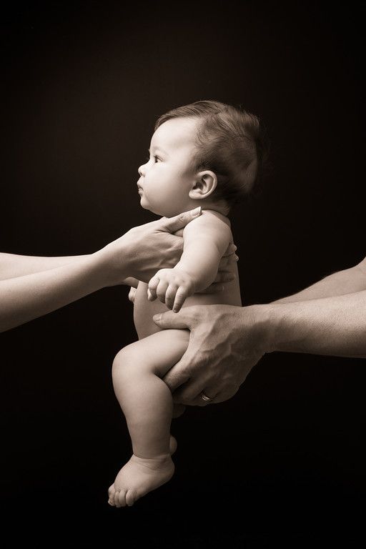 a woman holding a baby in her arms while another person holds it up with their hands