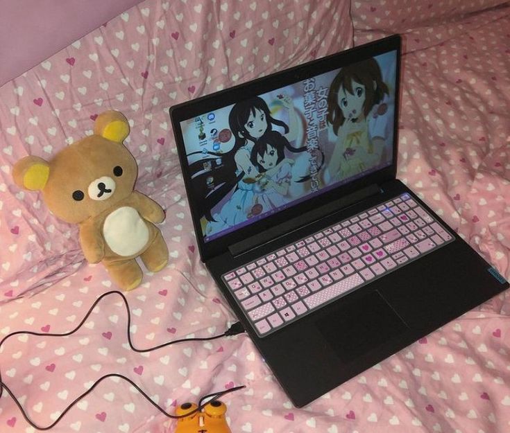 a teddy bear sitting next to a laptop computer on a bed with polka dot sheets