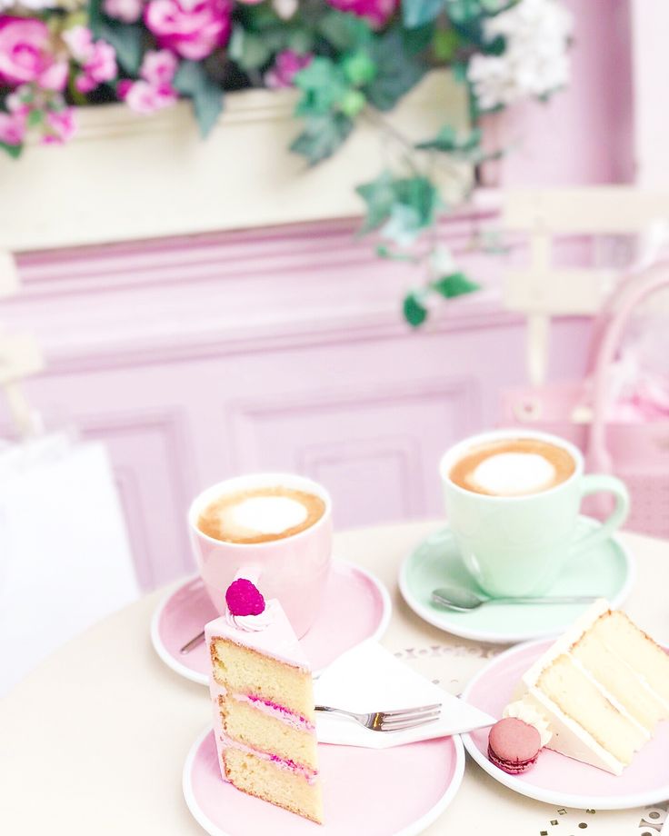 two slices of cake on pink plates with cups of coffee