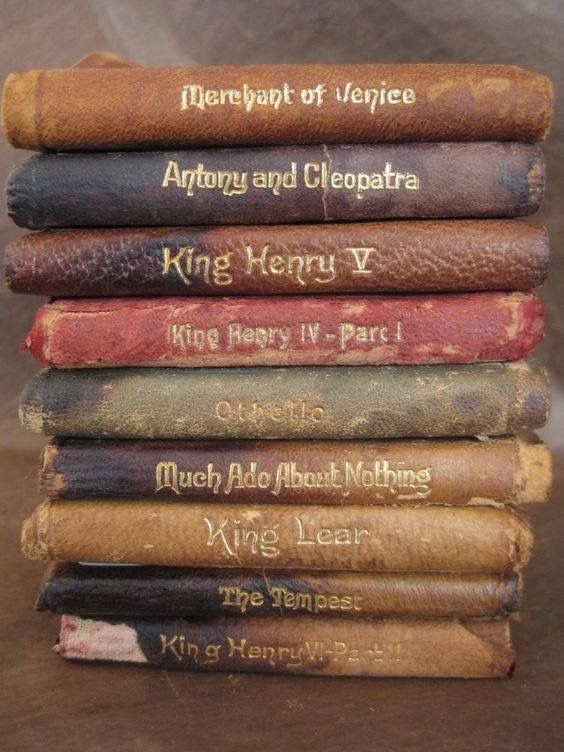 a stack of old books sitting on top of a wooden table next to each other