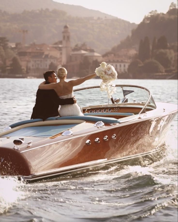 the bride and groom are riding in a speedboat on the water with their arms around each other