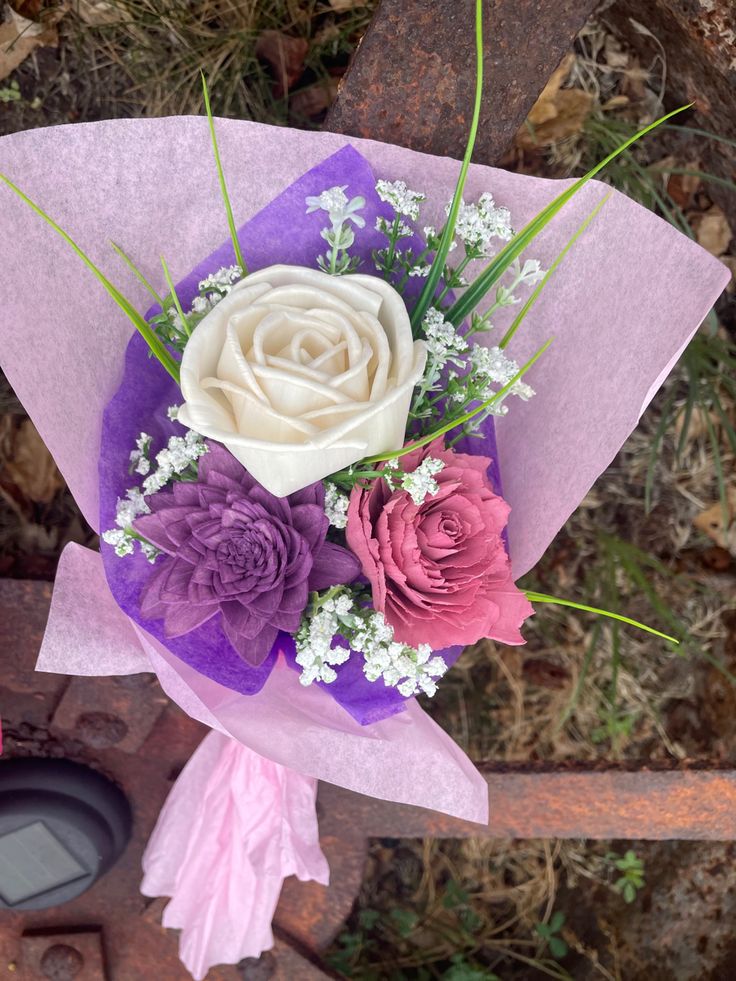 a bouquet of flowers sitting on top of a piece of purple and pink tissue paper