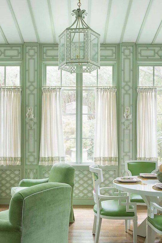 a living room filled with green furniture and lots of window coverings on the windowsill