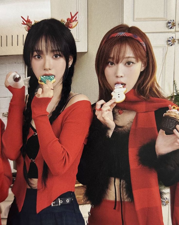 two women in red sweaters eating donuts and holding doughnuts with their hands