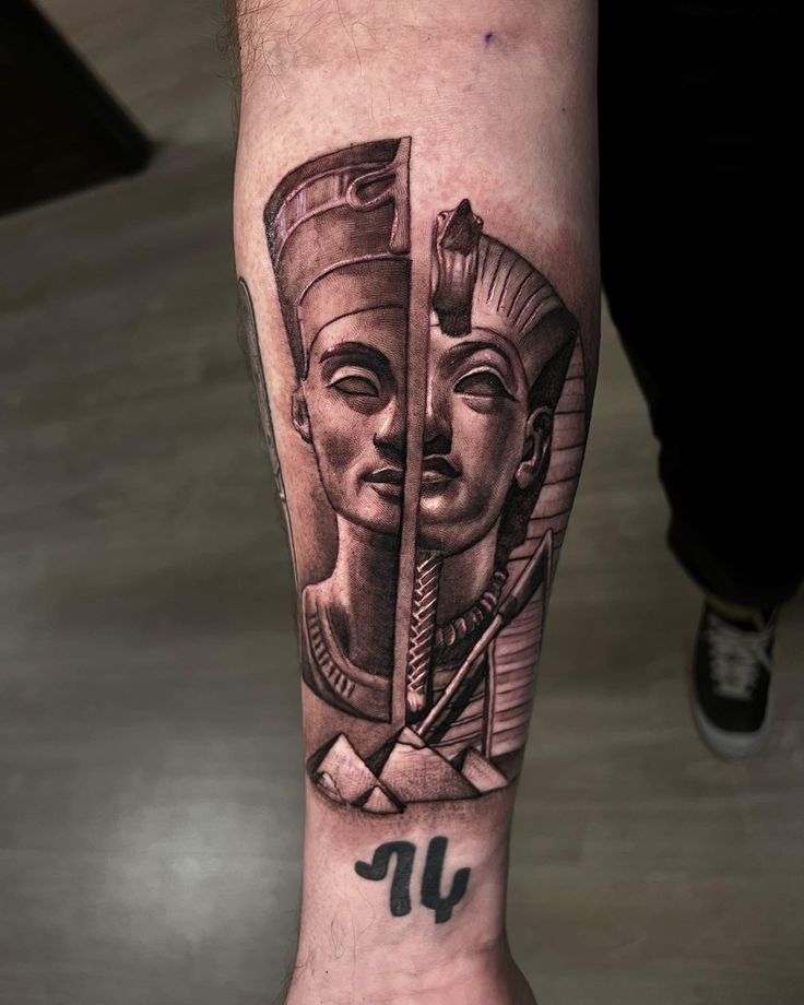 a man's arm with an egyptian mask on it and the letter j in black ink