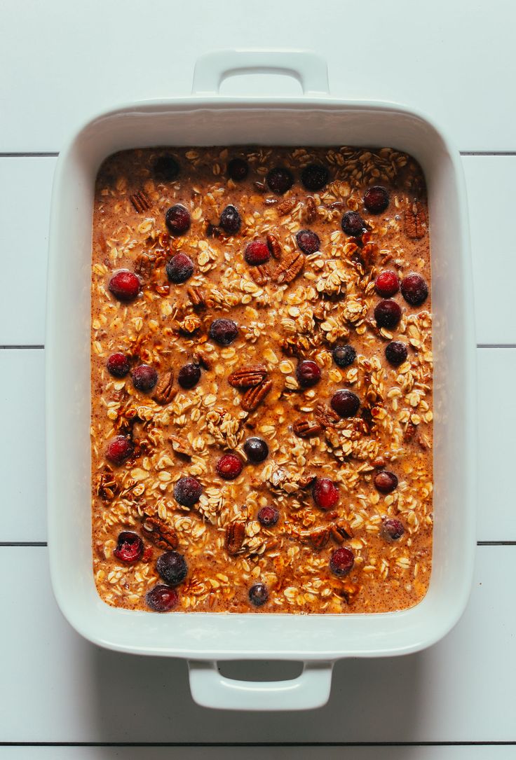 baked oatmeal in a white casserole dish with cranberries and pecans