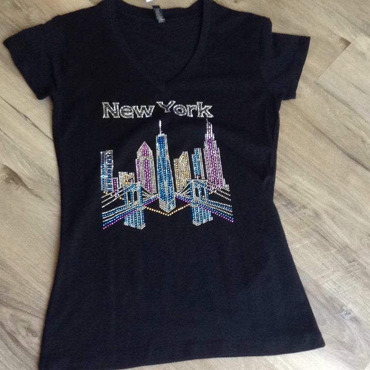 New York Graphic Tee In Size Medium But Most Likely To Be A Small Size. In Black With New York And Buildings In Rhinestones. Very Pretty V-Neck, Short Sleeves. Brand New With Tags! Measures Approximately: Pit To Pit (Chest) 16.5" Shoulder To Hem 26" Black V-neck Tops With Rhinestones, Black V-neck Top With Rhinestones, New York Graphic, City Graphic, City Woman, Top Tee, Graphic Tee, York City, Checks