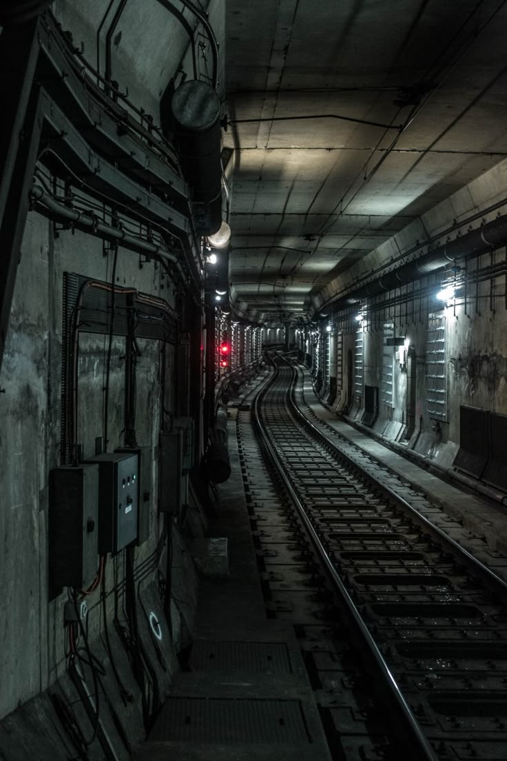 an empty train station with no people or trains on the tracks and lights at night