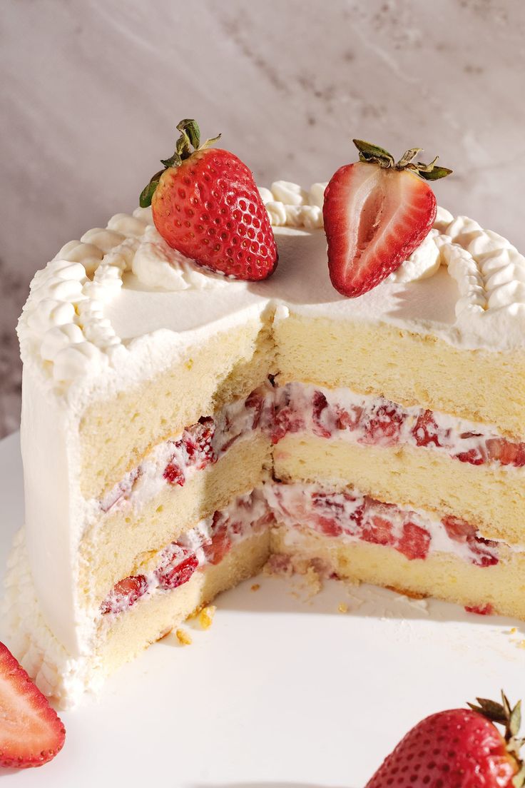 a white cake with strawberries on top and one slice cut out from the cake