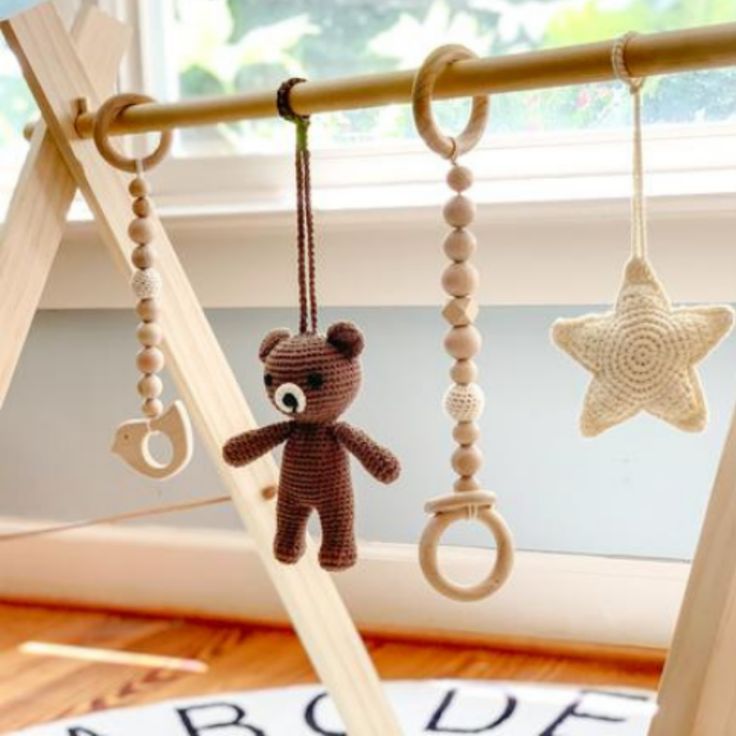 a crocheted teddy bear hanging from a wooden pole next to a star shaped object