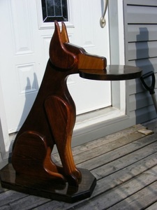 a wooden dog sitting on top of a table next to a white door with an umbrella