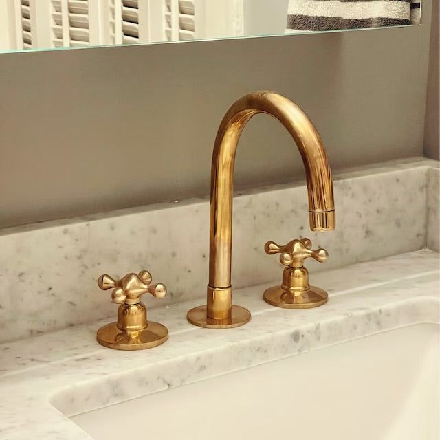 two golden faucets are sitting on the sink