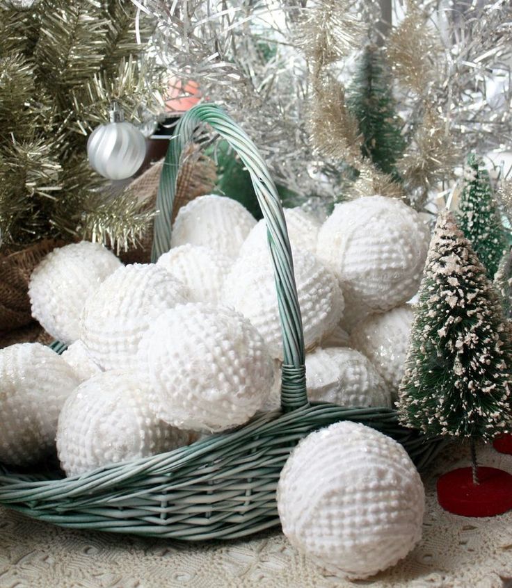 a basket filled with white balls sitting on top of a table next to christmas trees