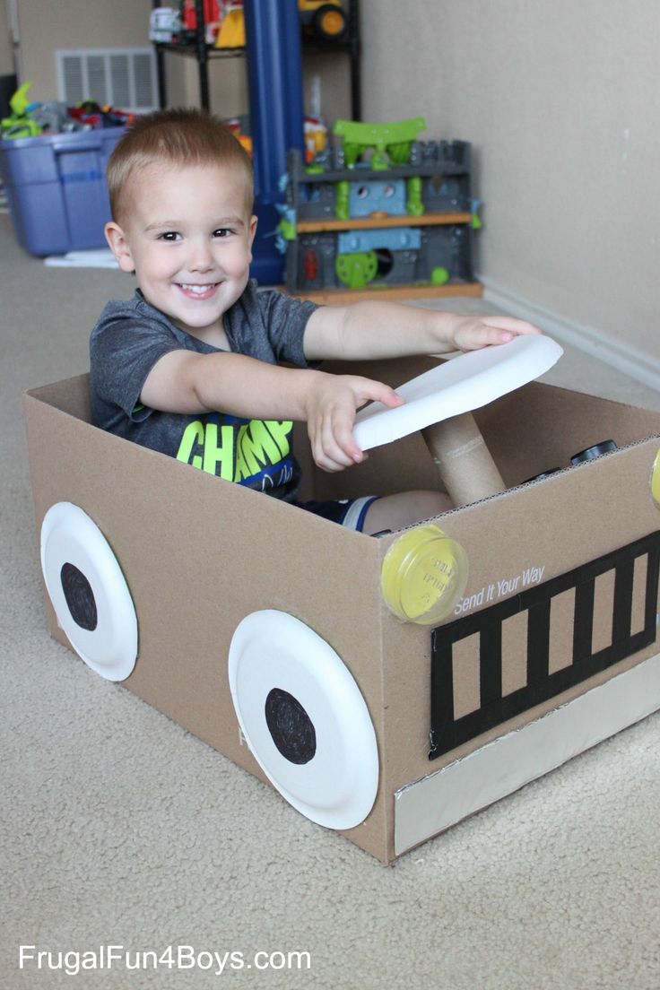 a young boy is sitting in a cardboard firetruck toy car that he made for his birthday party