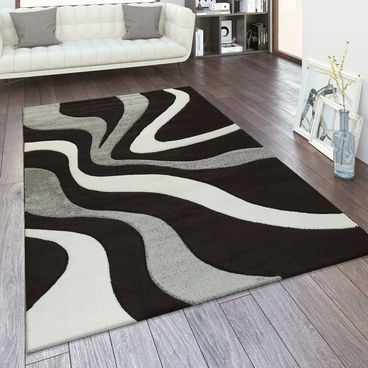 a living room with a white couch and brown rug on top of the wooden floor