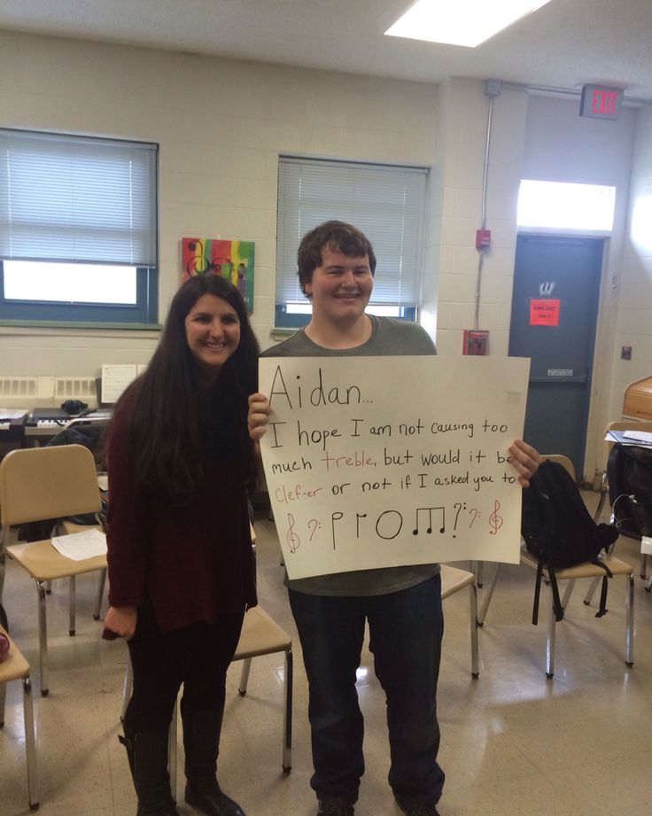 two people standing in a classroom holding up a sign