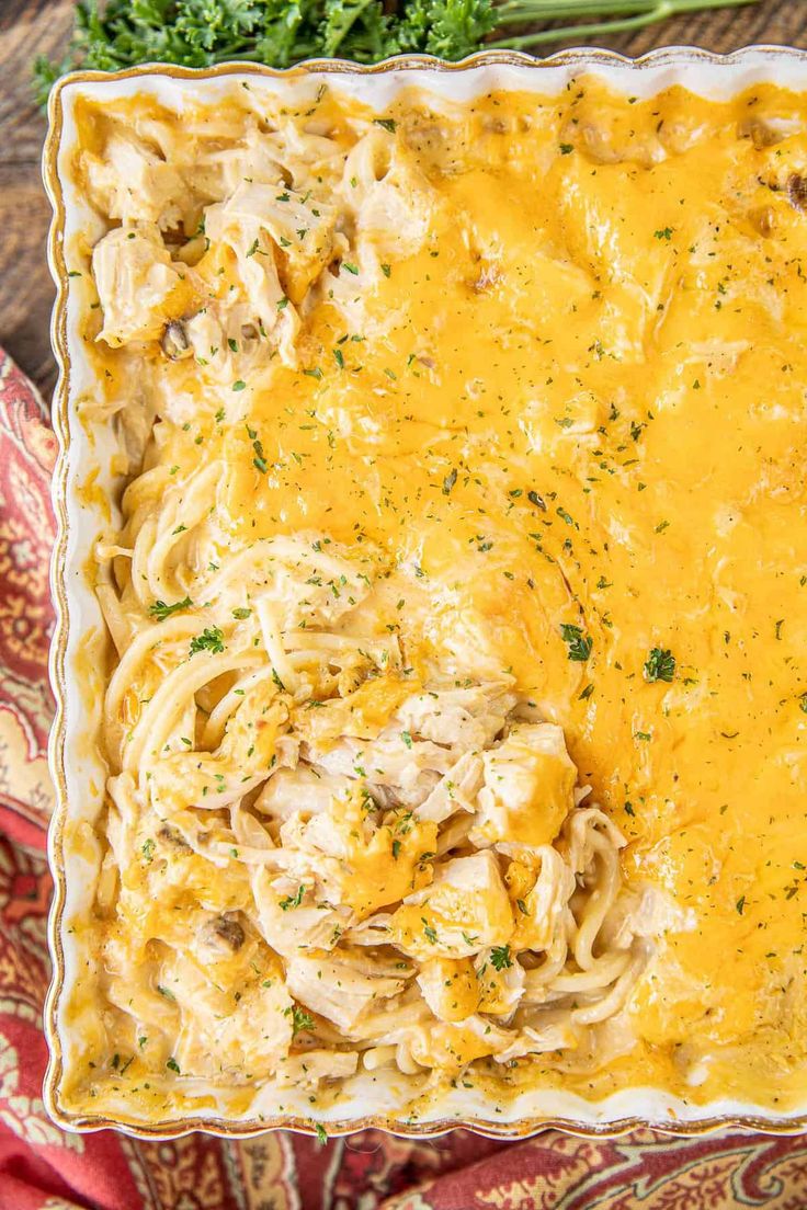 a casserole dish with chicken and noodles in a creamy sauce, garnished with parsley