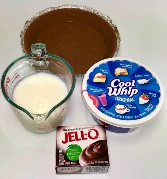 ingredients to make chocolate pudding including yogurt, cocoa whip and jello on a white surface