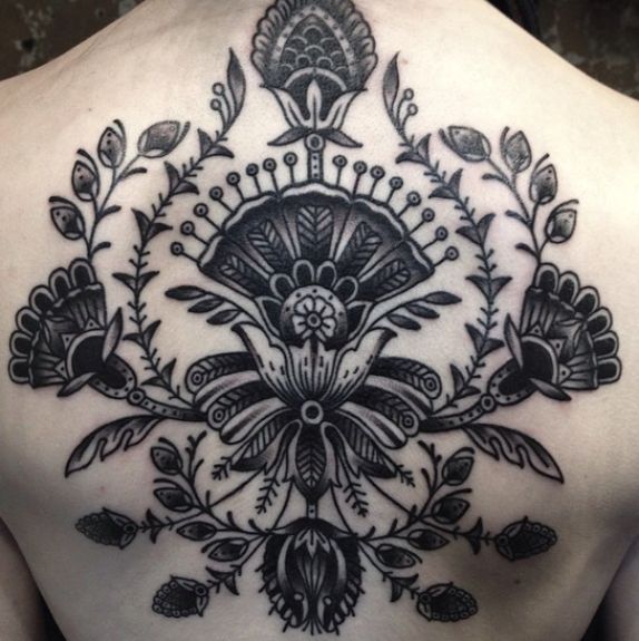 the back of a woman's shoulder with black and white tattoos on her chest