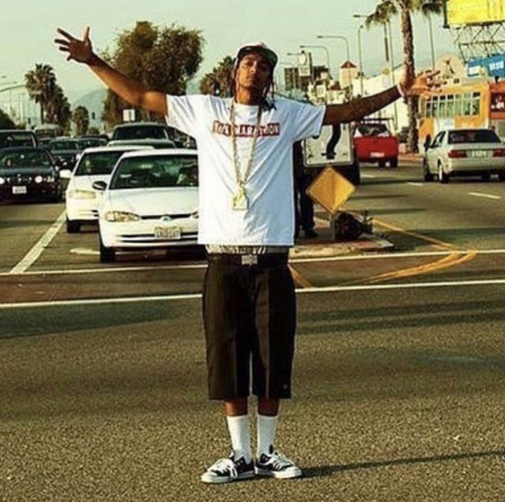 a man standing on the side of a road with his arms outstretched in front of him